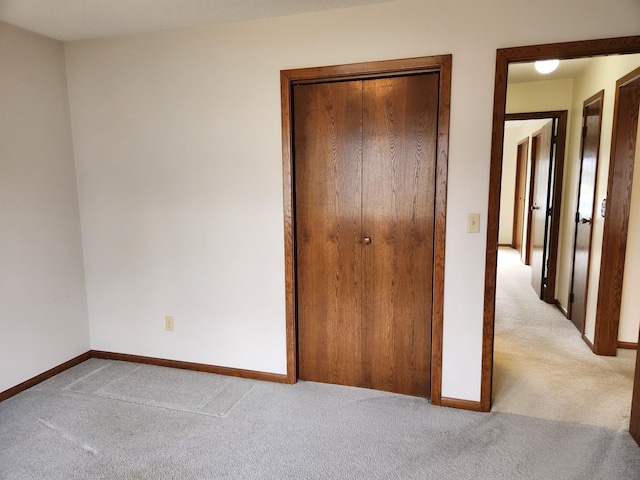 unfurnished bedroom with a closet, baseboards, and light colored carpet
