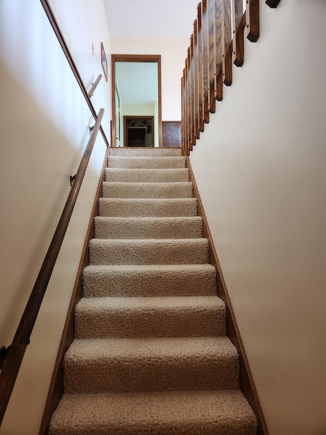 stairway with a wainscoted wall