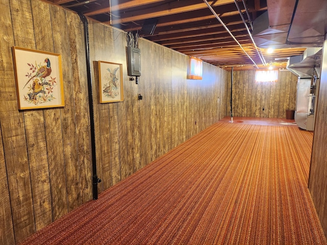 basement featuring wooden walls, carpet flooring, and electric panel
