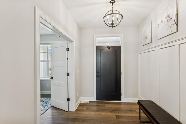 foyer entrance with baseboards, a chandelier, and dark wood-style floors