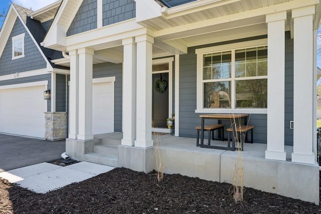 doorway to property with covered porch, an attached garage, and driveway