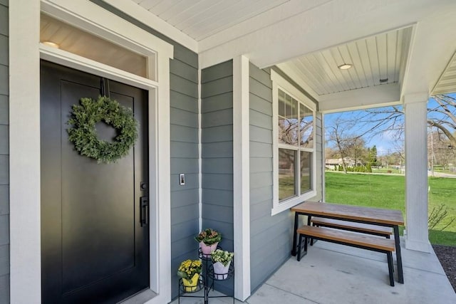 view of exterior entry featuring a porch and a lawn