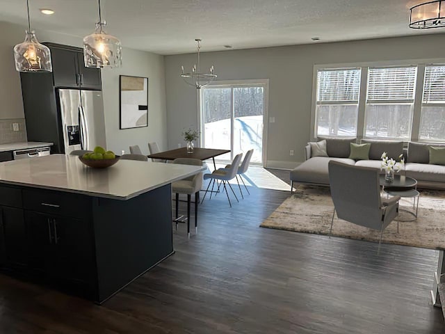 kitchen featuring stainless steel refrigerator with ice dispenser, light countertops, dark wood finished floors, and a chandelier