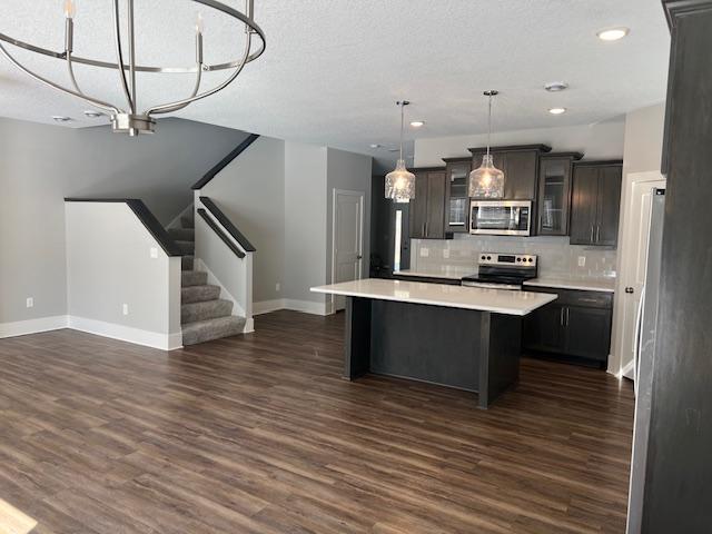 kitchen with backsplash, a kitchen island, appliances with stainless steel finishes, light countertops, and open floor plan