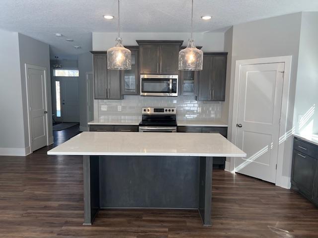 kitchen featuring decorative backsplash, appliances with stainless steel finishes, dark wood finished floors, light countertops, and baseboards