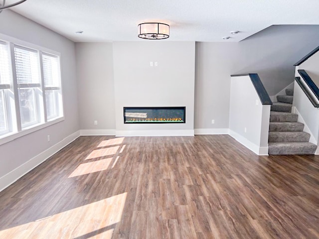 13357 Two Mile Rd, Brainerd, MN 56401 - unfurnished living room with wood finished floors, a glass covered fireplace, baseboards, and stairway