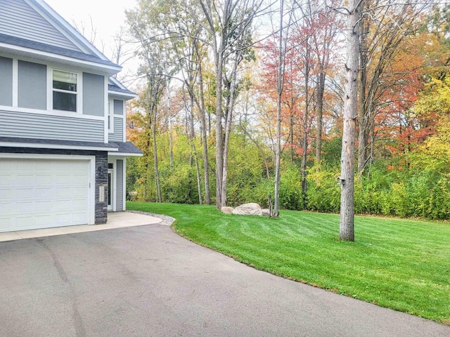 13357 Two Mile Rd, Brainerd, MN 56401 - view of grassy yard featuring a garage and asphalt driveway