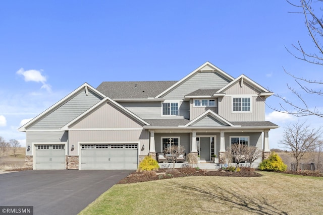 craftsman-style home featuring a shingled roof, an attached garage, stone siding, covered porch, and aphalt driveway