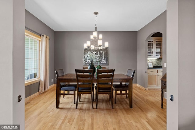dining space with a chandelier, light wood-style floors, and baseboards