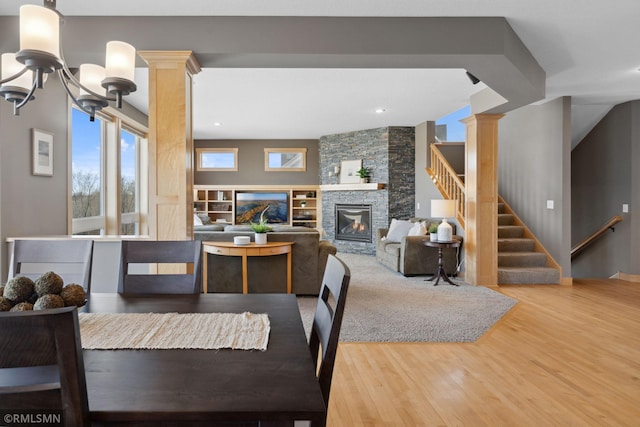 dining space with a fireplace, recessed lighting, a chandelier, wood finished floors, and stairs