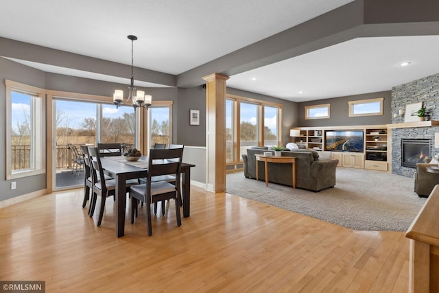 dining room featuring a wealth of natural light, a chandelier, light wood-style floors, and a fireplace