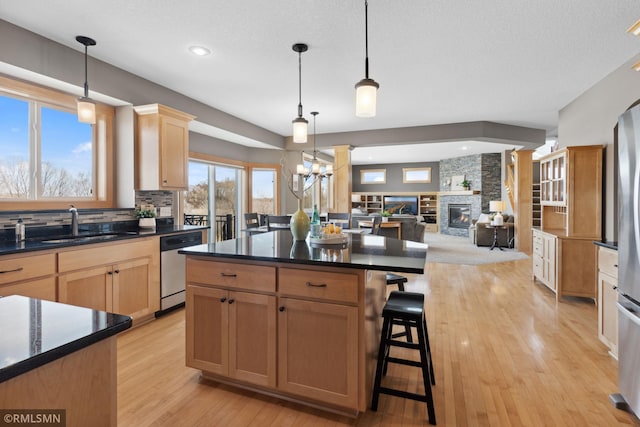 kitchen featuring a sink, dishwasher, dark countertops, and a fireplace