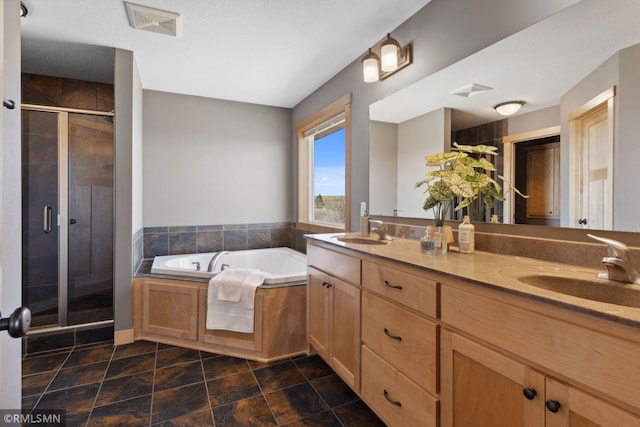 full bath featuring a sink, double vanity, a stall shower, and a garden tub