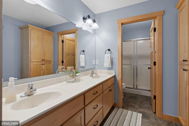 full bathroom with a shower stall, double vanity, a sink, and toilet