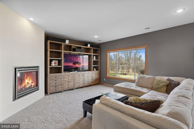 carpeted living room with a glass covered fireplace and recessed lighting
