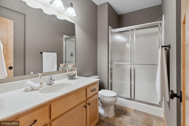 bathroom with toilet, a stall shower, and vanity