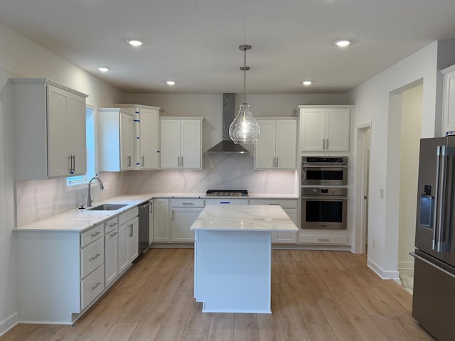 kitchen with wall chimney exhaust hood, appliances with stainless steel finishes, a sink, light wood-style floors, and recessed lighting