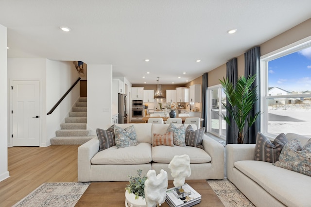 living room featuring light wood finished floors, stairs, and recessed lighting
