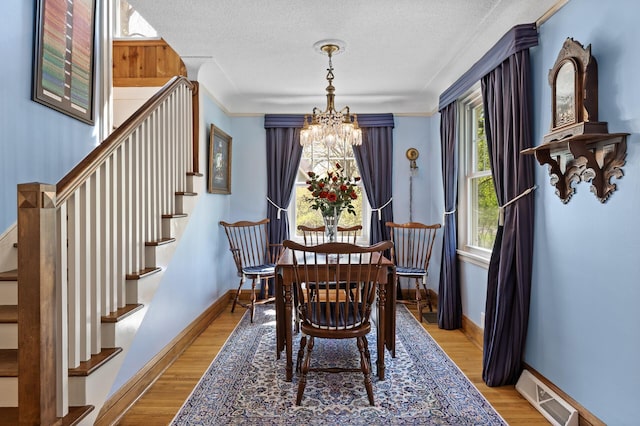 3021 Atwater St, Hopkins, MN 55305 - dining room featuring a chandelier, stairway, a textured ceiling, and wood finished floors