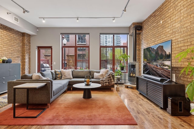 living room featuring track lighting, light wood-style flooring, and brick wall