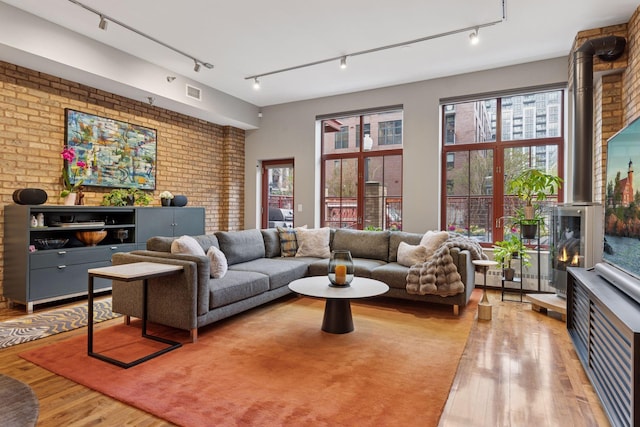 living room with wood finished floors, track lighting, and brick wall