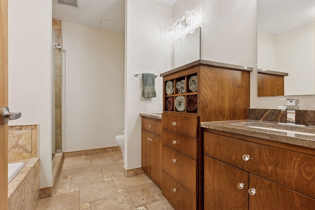 full bath with stone tile flooring, toilet, vanity, a stall shower, and a bath
