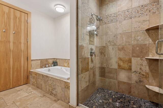 full bathroom with a shower stall, stone tile floors, and a garden tub