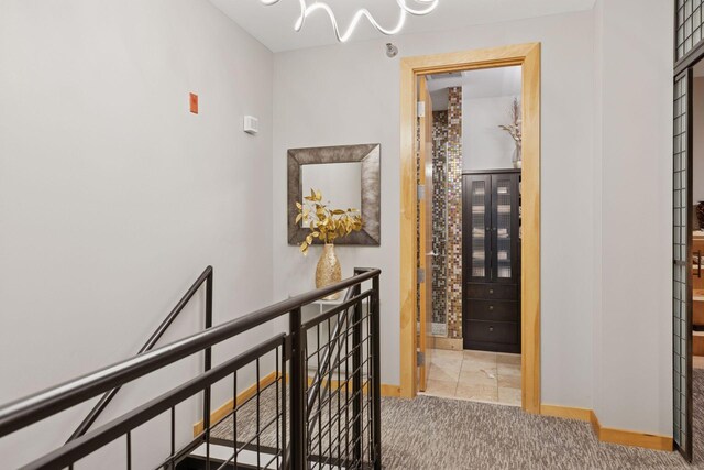 hall with an upstairs landing, carpet floors, and baseboards
