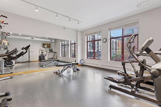 workout area featuring a baseboard radiator and baseboards