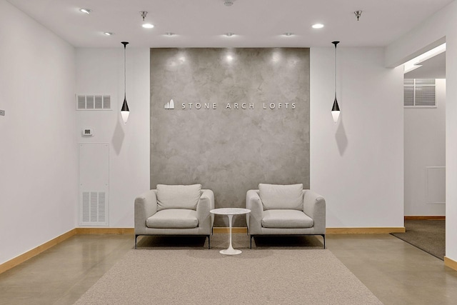 sitting room featuring finished concrete flooring, baseboards, and recessed lighting