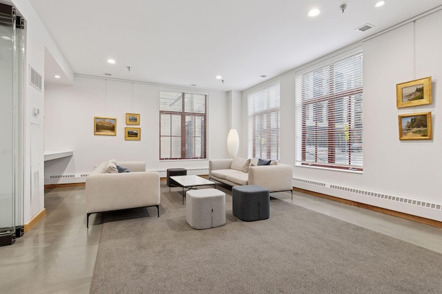 living room featuring recessed lighting, baseboard heating, baseboards, and finished concrete flooring