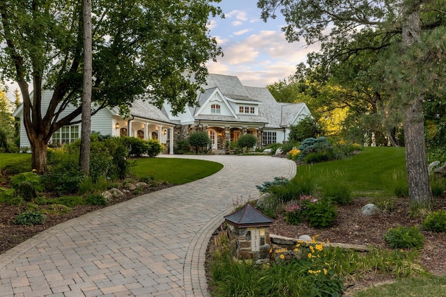 view of front of home featuring a front yard, curved driveway, and stone siding