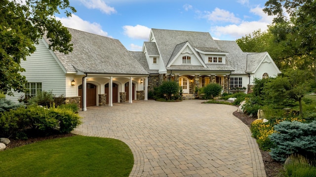 view of front of house with a garage, stone siding, and curved driveway