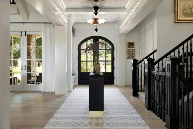 foyer entrance featuring crown molding, french doors, wood finished floors, and stairs