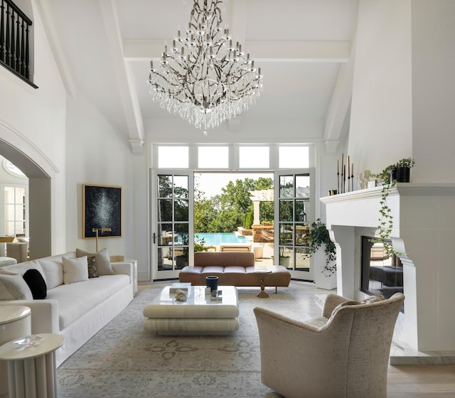 living area featuring a chandelier, a towering ceiling, beamed ceiling, and a premium fireplace