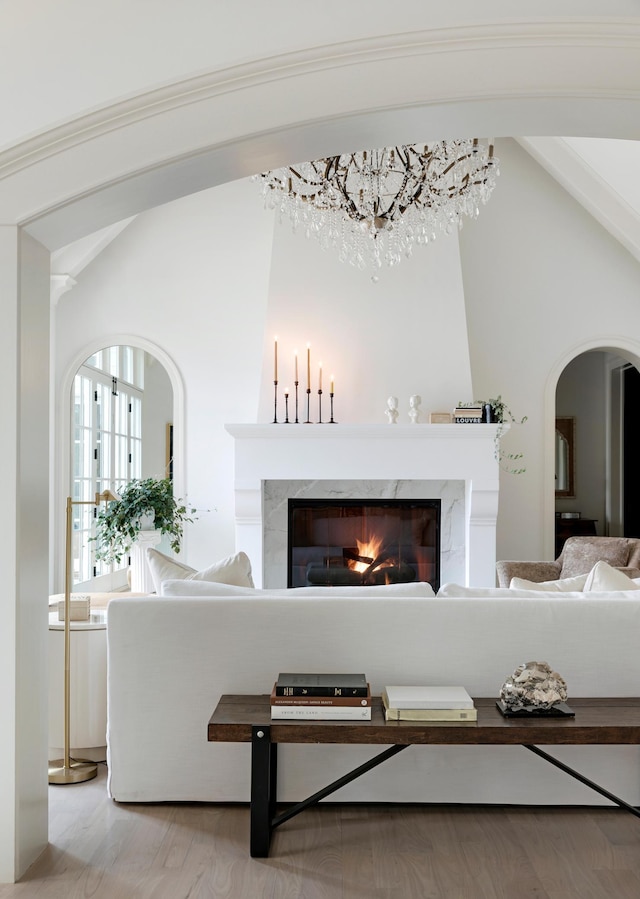 interior space with wood finished floors, arched walkways, and a premium fireplace