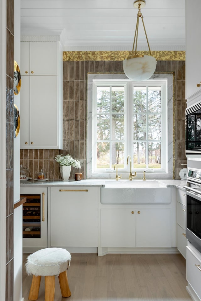 kitchen with a sink, light countertops, wine cooler, stainless steel oven, and built in microwave