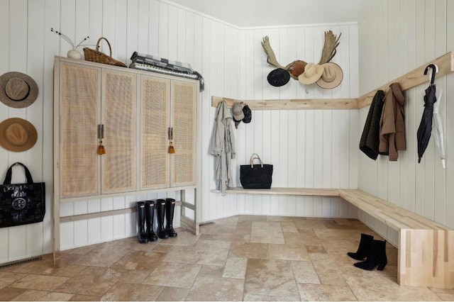 mudroom featuring stone tile floors and wooden walls