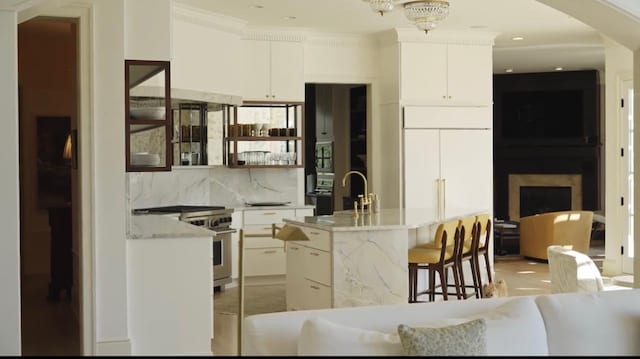 kitchen with a sink, high quality appliances, arched walkways, and white cabinetry