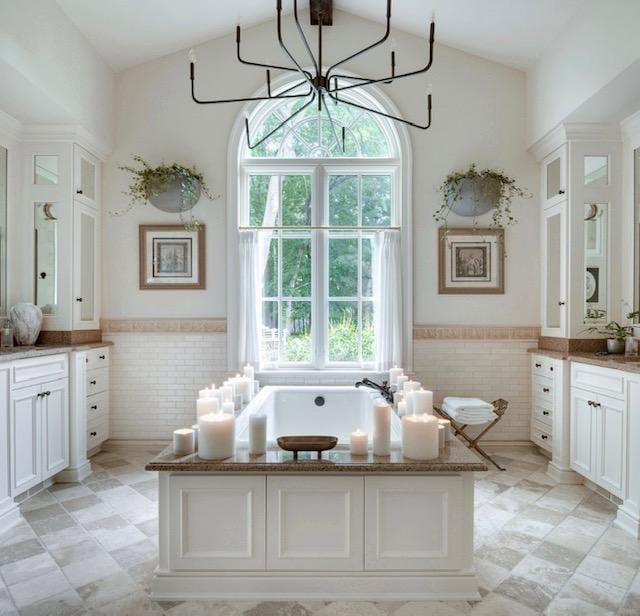 full bathroom with a garden tub, vanity, a wainscoted wall, and tile walls