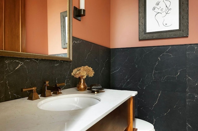 half bath with toilet, tile walls, and vanity