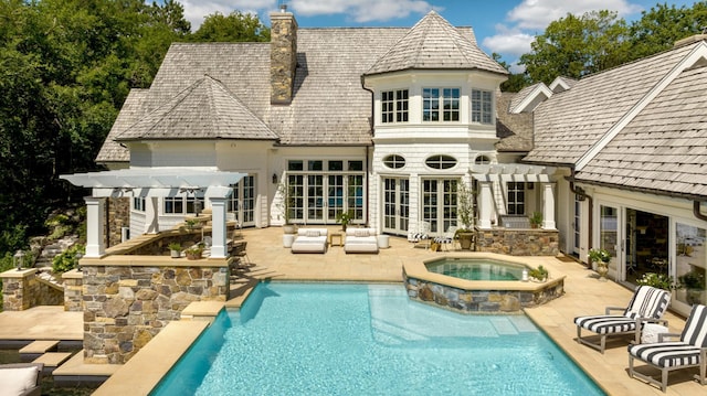 rear view of house with a pergola, a pool with connected hot tub, a chimney, a patio area, and french doors