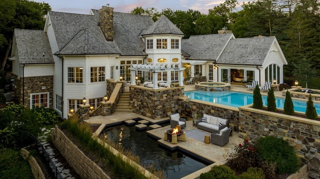 back of house with an outdoor living space with a fire pit, stairway, a patio, and a chimney