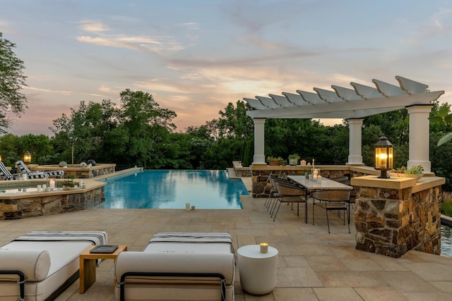 view of swimming pool with a pergola, a patio area, outdoor dry bar, and exterior kitchen