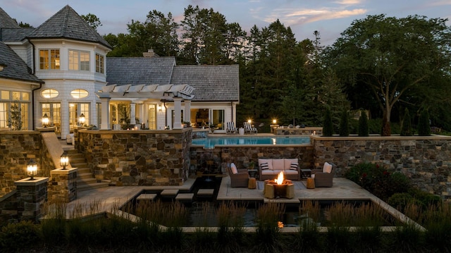 back of house featuring an outdoor living space with a fire pit, a patio, a chimney, and an outdoor pool