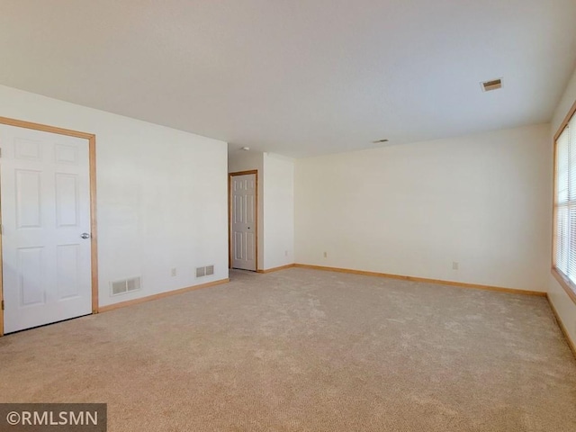 spare room with visible vents, baseboards, and light carpet