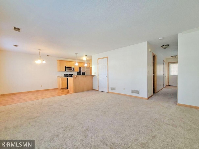 unfurnished living room with visible vents and light carpet