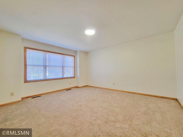 carpeted spare room with baseboards and visible vents