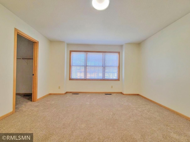 unfurnished bedroom featuring visible vents, baseboards, a closet, carpet, and a walk in closet