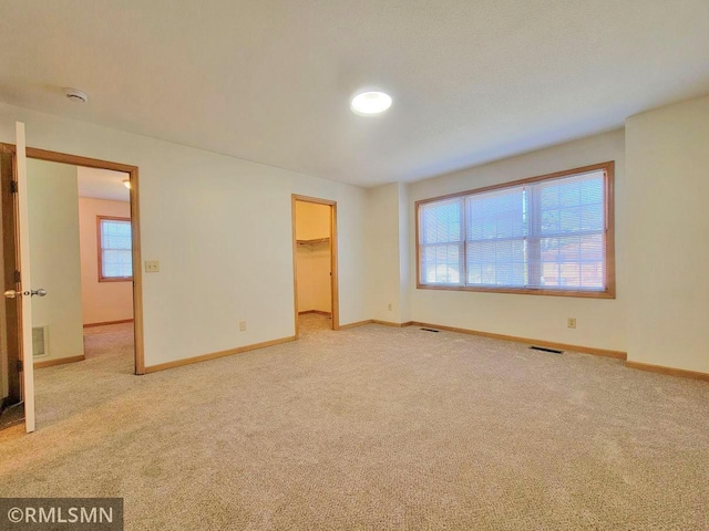 unfurnished bedroom featuring baseboards, multiple windows, and carpet